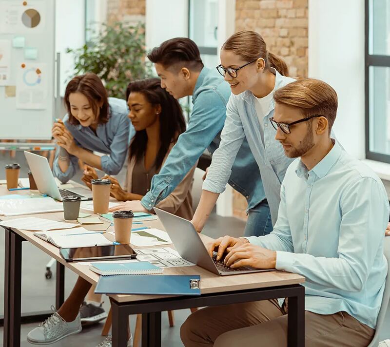 A team collaborating around laptops at a shared table