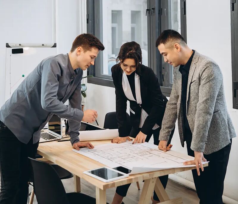 Colleagues reviewing plans spread across a table