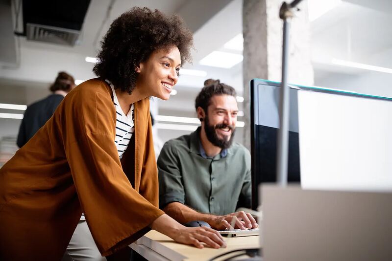 Two colleagues smiling while working at a computer