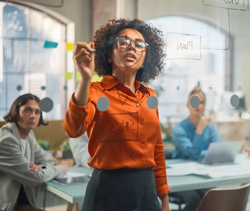 A team member presenting ideas on a glass board