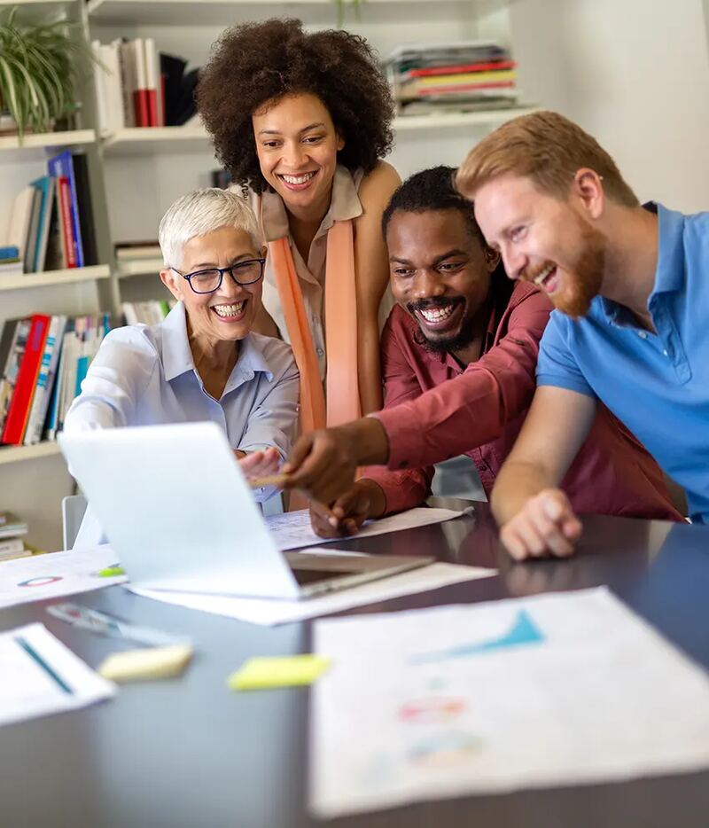 A smiling team gathered around a laptop