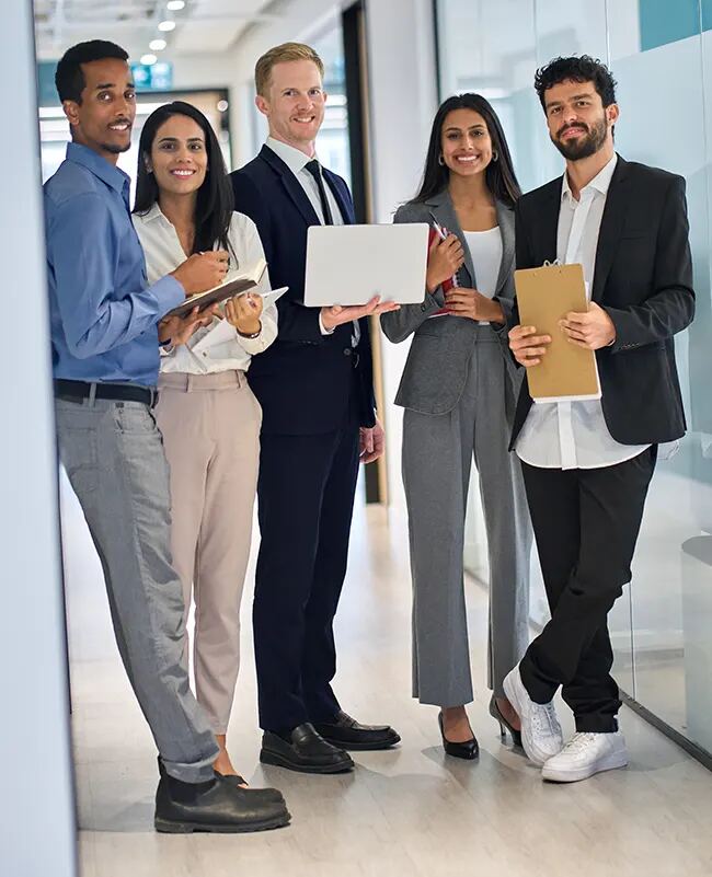 A smiling team standing together in an office hallway