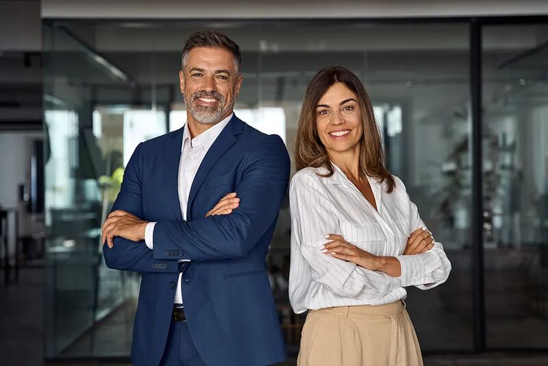 Two smiling business professionals standing with arms crossed