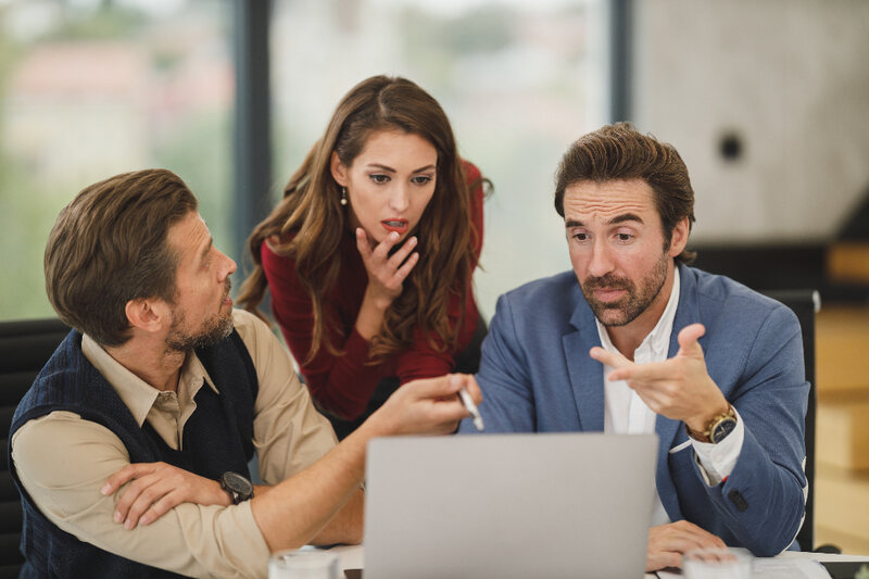 Three colleagues reviewing a sales campaign plan together at a laptop