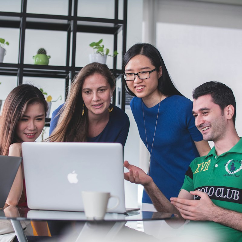 A young, smiling ABC Marketing team gathered around a laptop