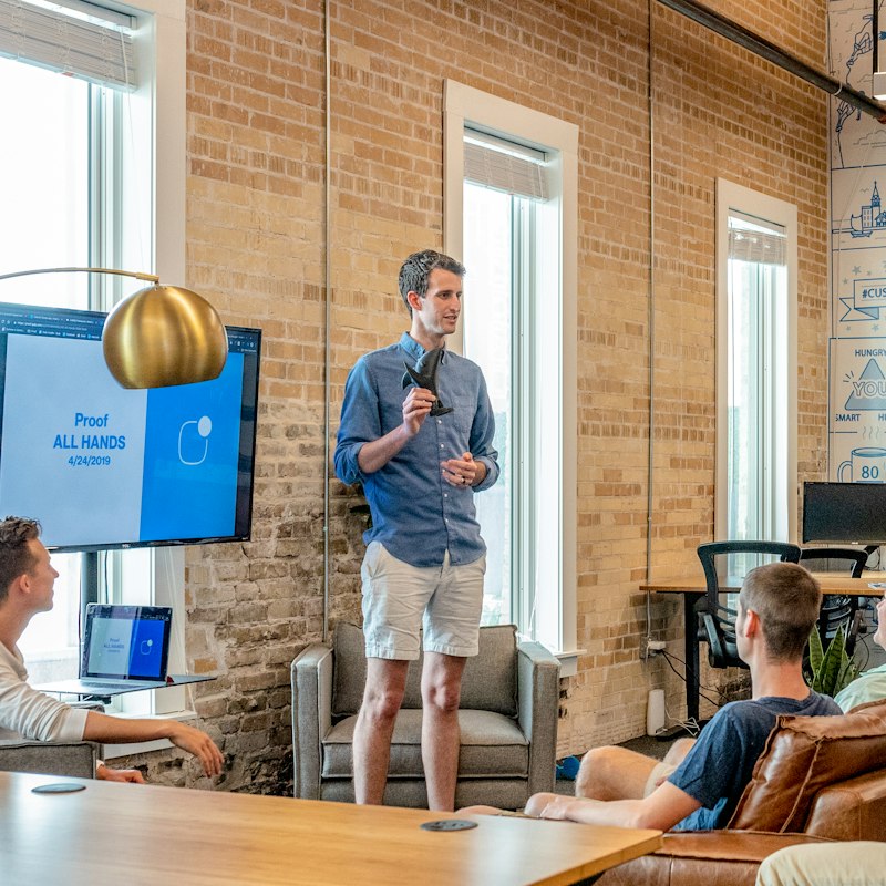 A trainer presenting to an engaged team in a brick-walled office