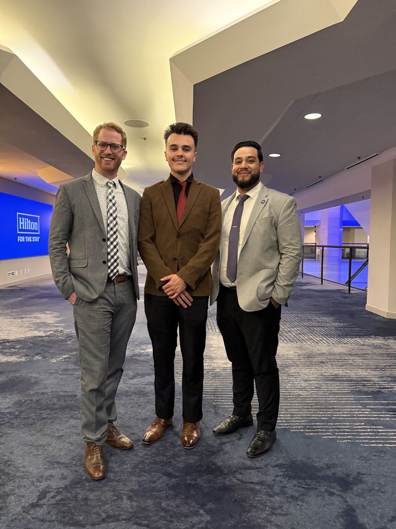 Three Clarity Acquisitions leaders in suits at a hotel conference