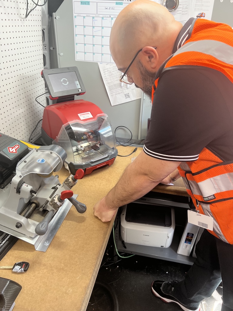 Technician using precision key cutting machine in service van