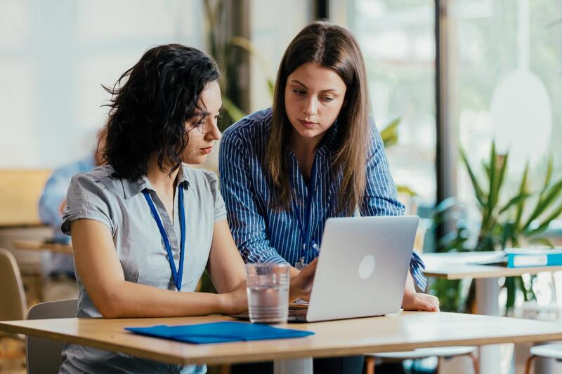 Two colleagues reviewing work on a laptop