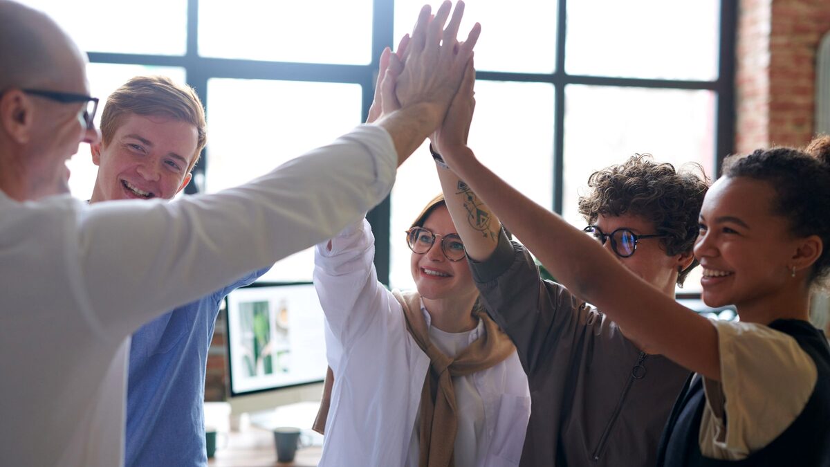 A sales and marketing team celebrating a win together in a bright office