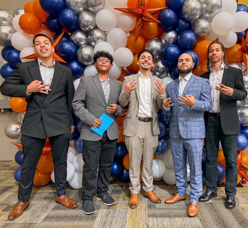 Five Mission III Management team members posing in front of a balloon wall