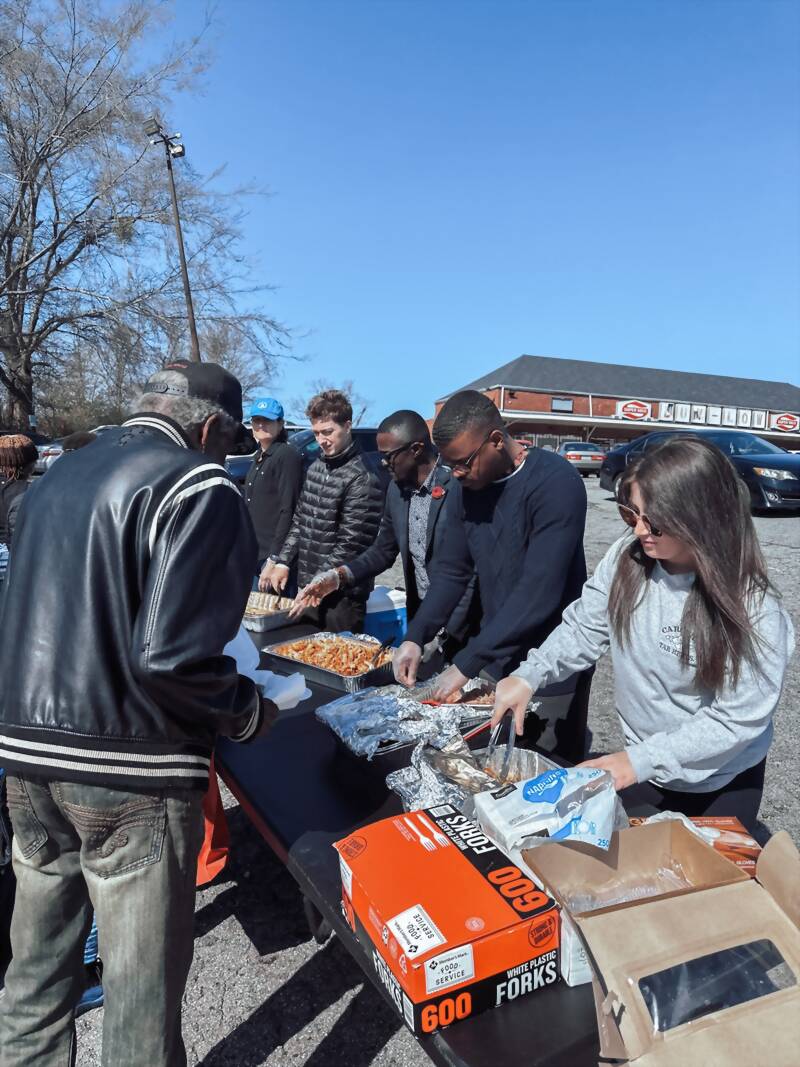 New Acquisitions volunteers serving meals at a community outreach event