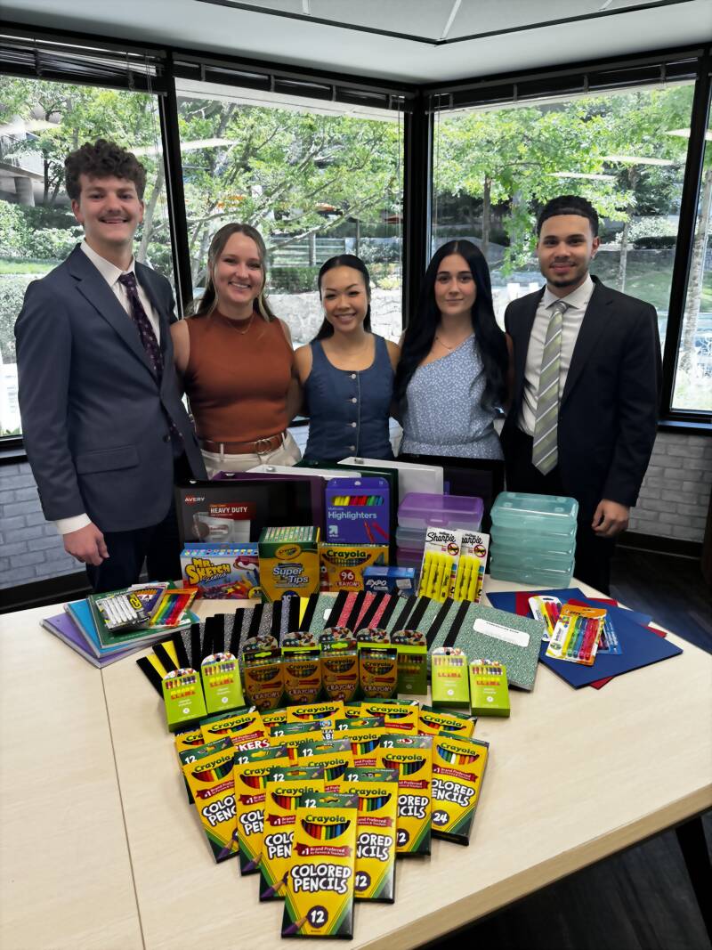 New Acquisitions team members with school supplies collected for local students