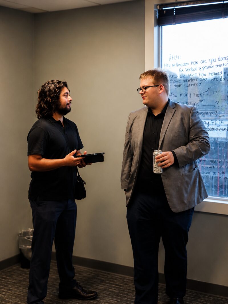 Two NoeCee Global team members talking through a campaign beside the office whiteboard