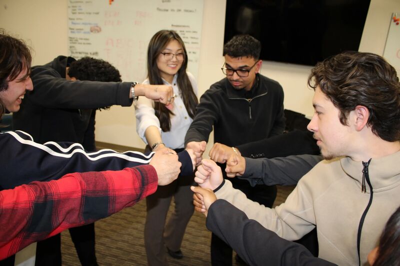 Sora Acquisitions team members joining fists in a team huddle