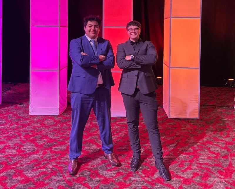 Two Super Nova Marketing team members posing in front of stage lights at a company event