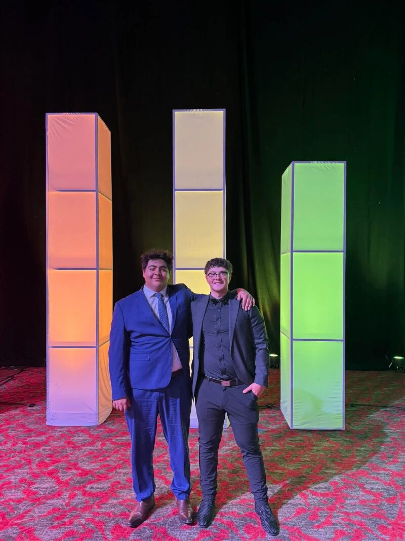 Two Super Nova Marketing team members in suits between illuminated stage pillars