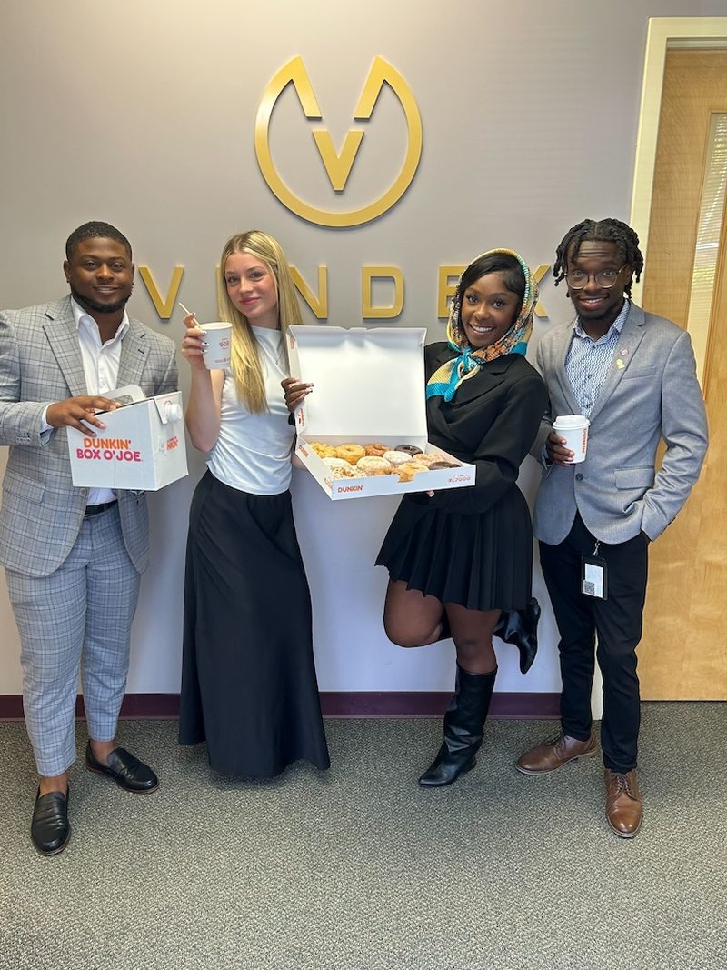 Vendex team members in the office beneath the company logo
