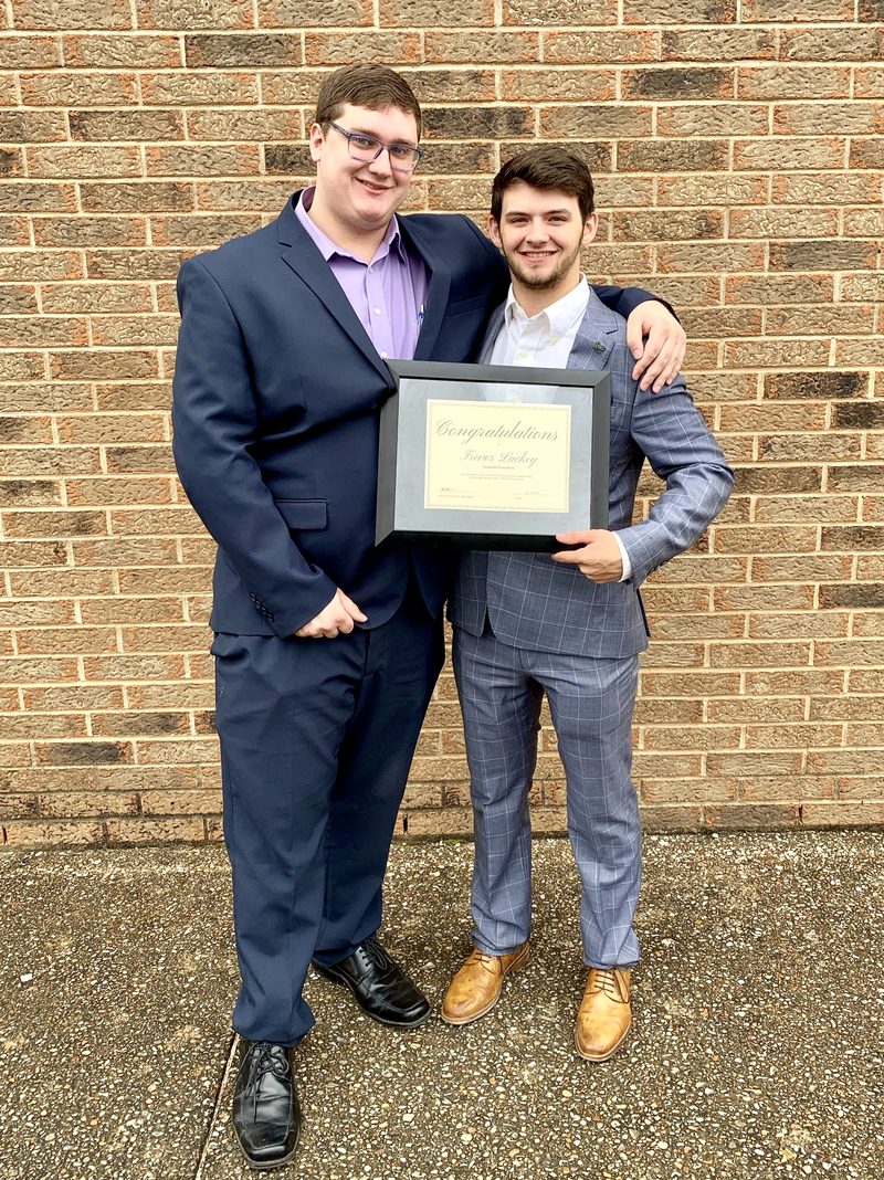 Two Vendex team members holding a company recognition award